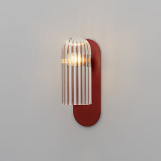 Wall-mounted light fixture with red base and glass shade on a gray background