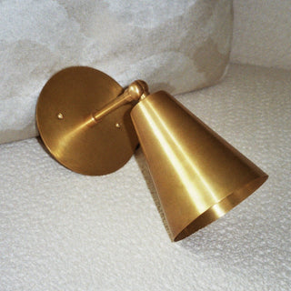 brass wall sconce on a textured white surface